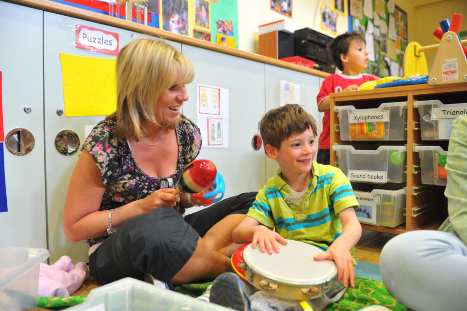 a child and teacher play with musical instruments