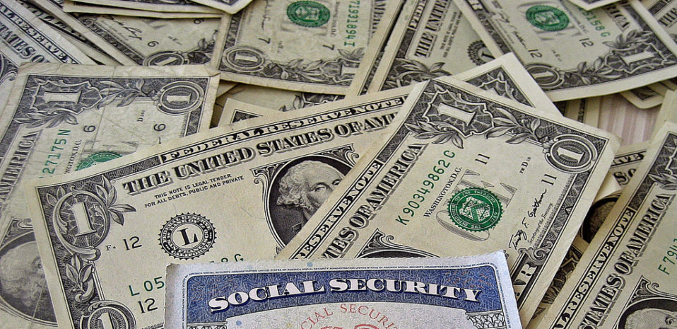 Dollar bills scattered across a table with a social security card on top