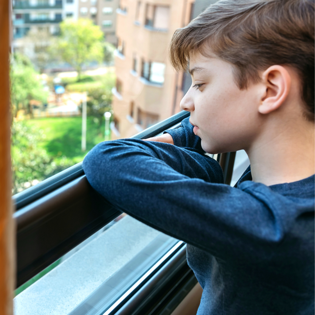 Photo of child looking out of a window