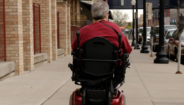 Photo of person using a power wheelchair on a sidewalk