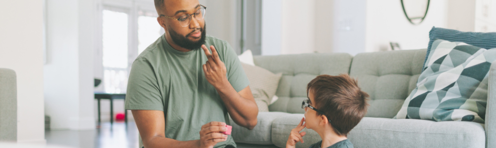 Man and kid doing sign language and playing with blocks on the living room floor