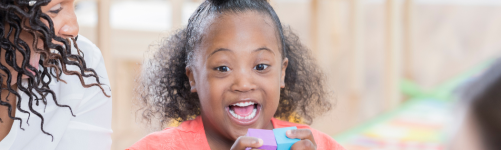 Young student excited sitting on a carpet in a classroom