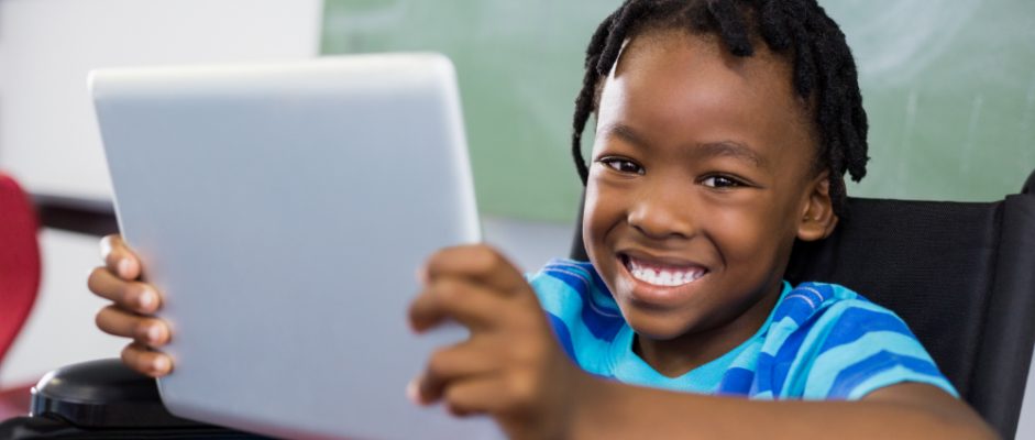 Young Black child in a wheelchair using a tablet for school